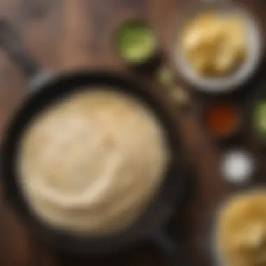 A flat cast iron skillet with freshly cooked tortillas stacked on a wooden table